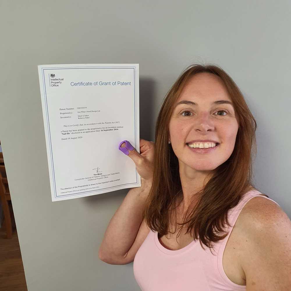 Thumble Baby Care founder holding the UK patent certificate while wearing a purple Thumble.