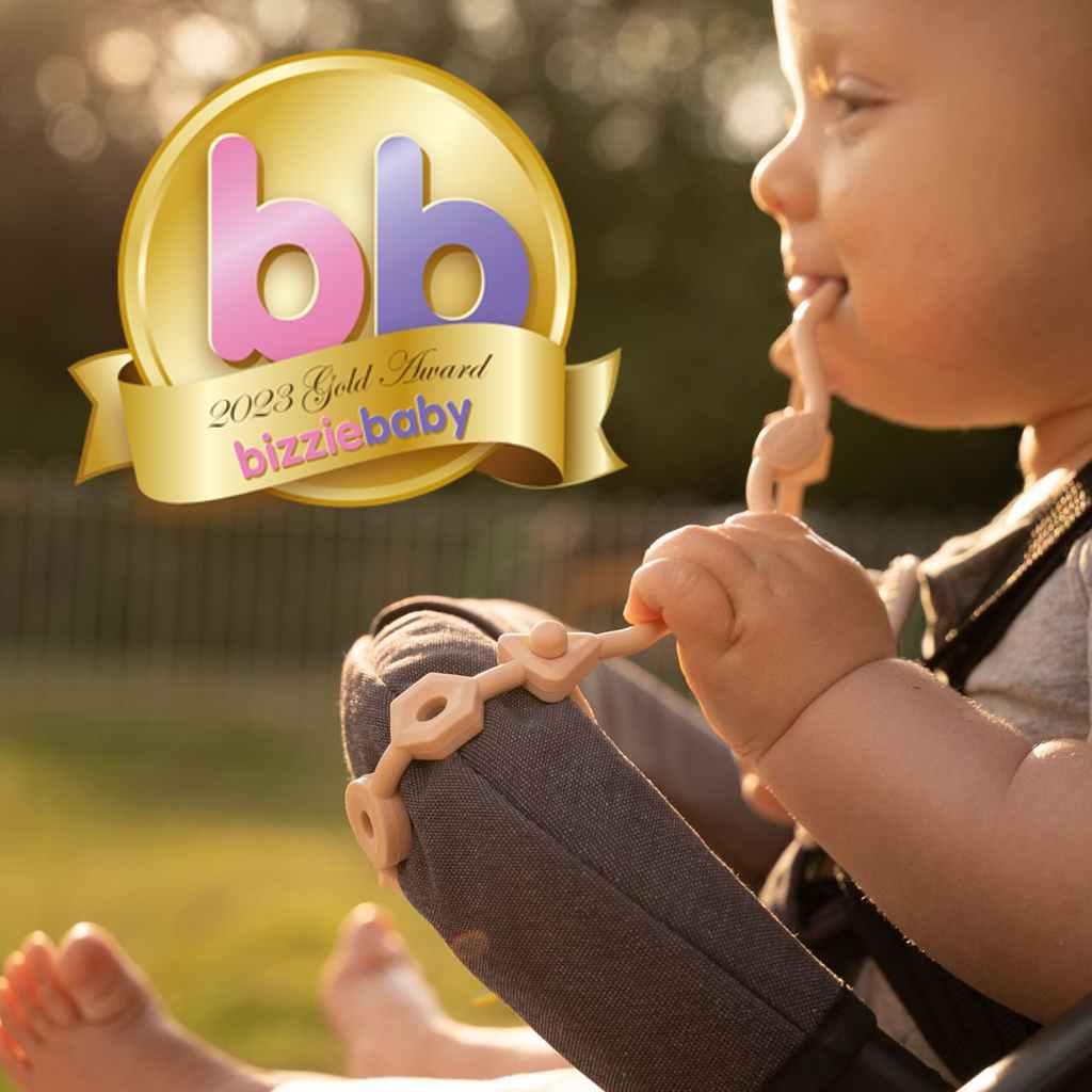 Baby chewing a blush pink Squiggle Strap on a buggy bar with bizziebaby 2023 Gold Award, by Thumble Baby Care.