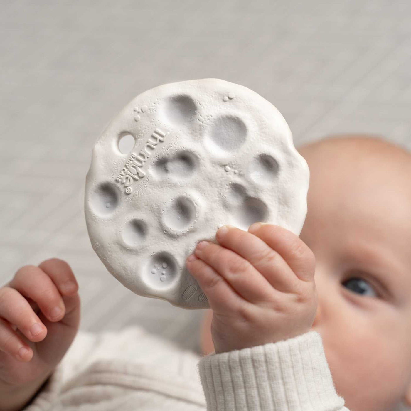 Moon Biscuit Natural Rubber Space Toy held by a baby by Thumble Baby Care