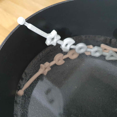 Squiggle Strap Silicone Toy Strap being sterilized in a pan of boiling water by Thumble Baby Care